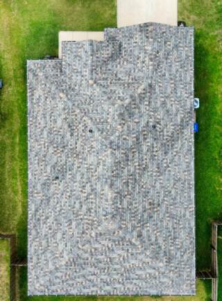 Aerial view directly overhead of the home showing the new 30 year Class 3 IKO Dynasty architectural shingles in Cornerstone Weatherwood along with new seamless gutters in dark bronze